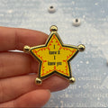 A gold and yellow star-shaped enamel pin held by a hand. The pin features the text 'I knew it I knew you' in black, surrounded by a red wavy line pattern and gold metallic edges.
